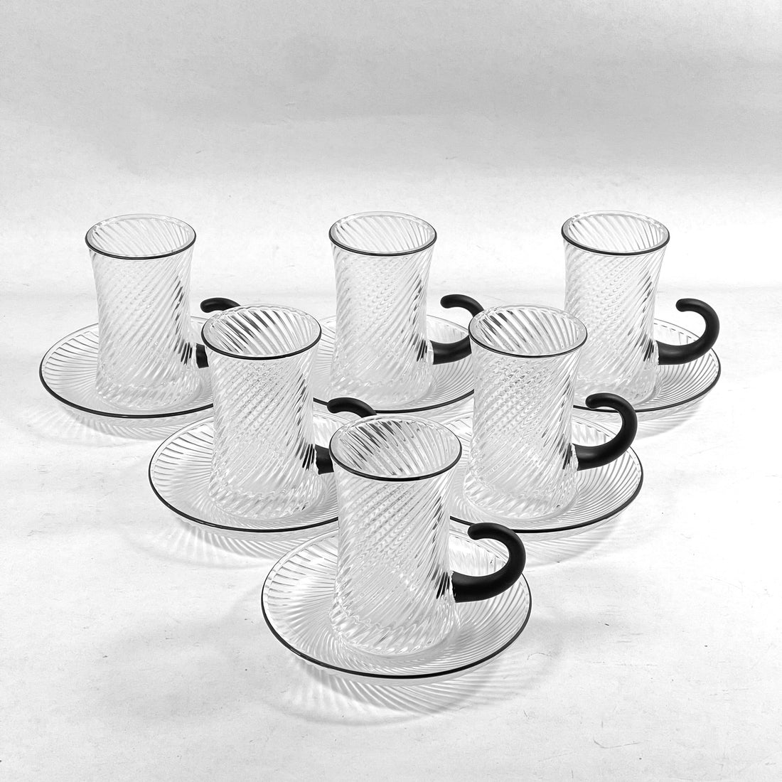 Set of clear glass cups with black handles on a white background