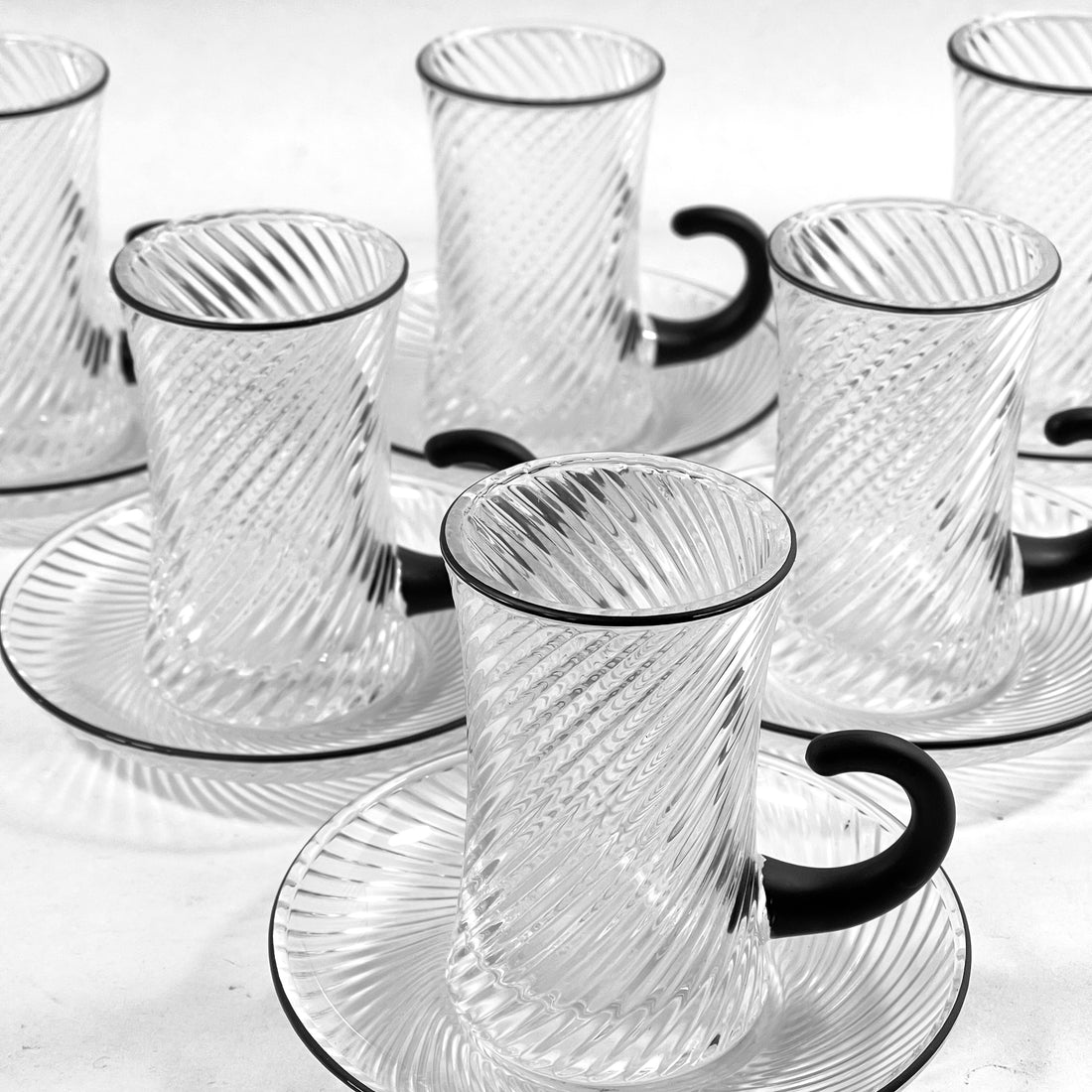 Set of clear glass cups with black handles on a white background